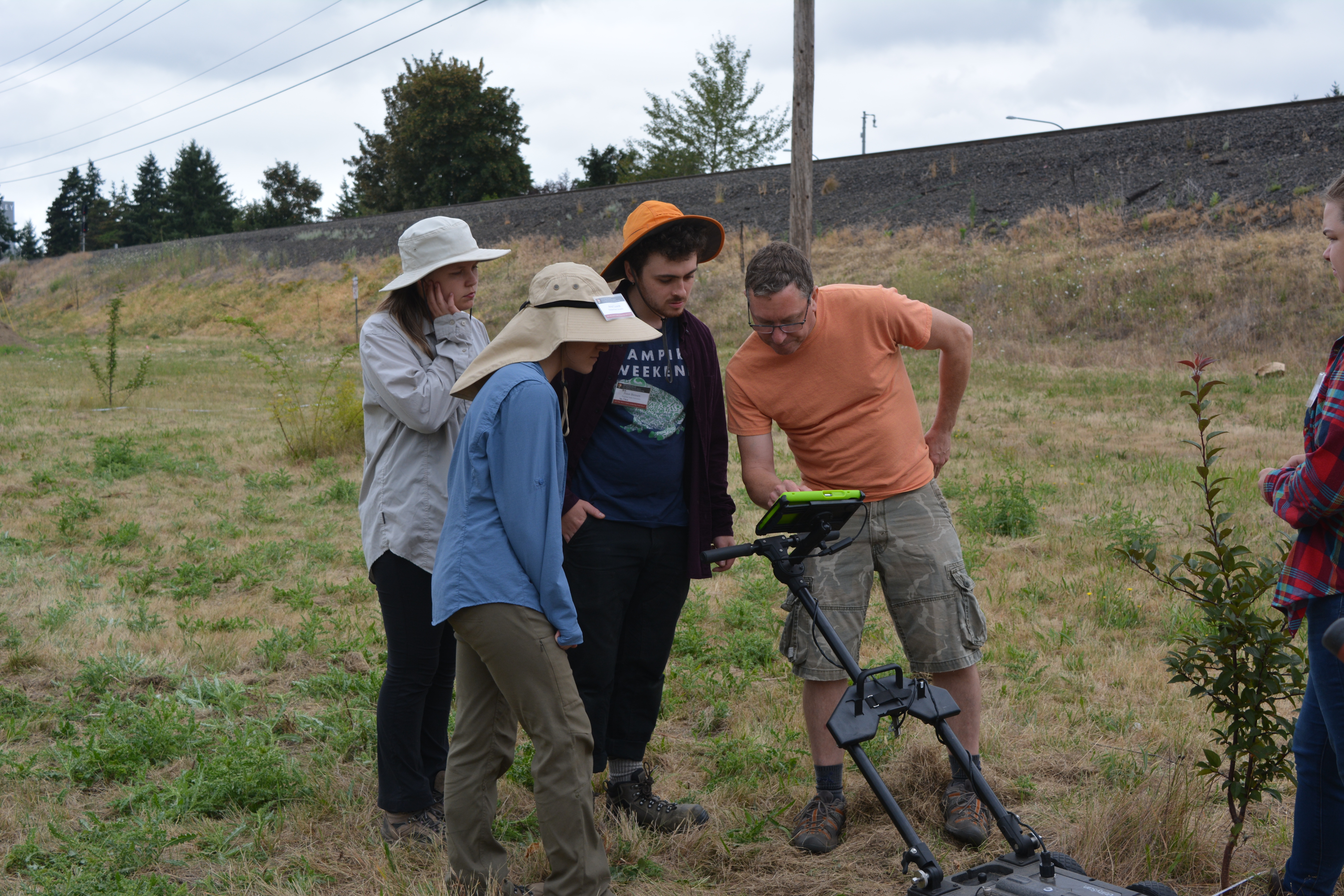 Three students getting trained on ground-penetrating radar in field